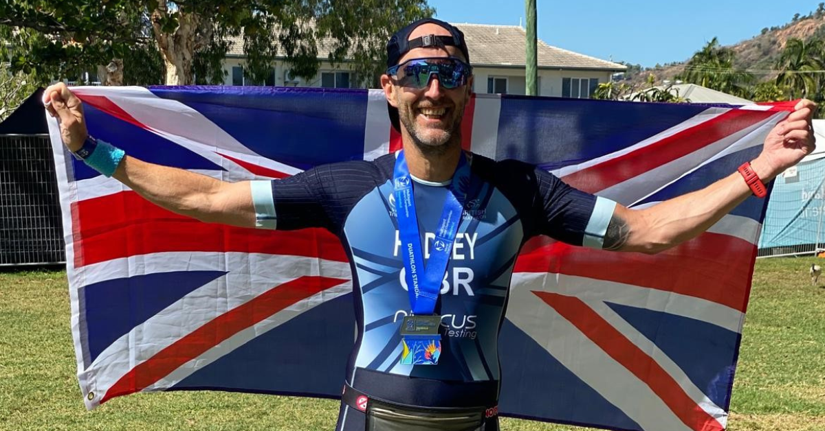 Photo of Stu Hadley holding a UK flag with a smile on his face